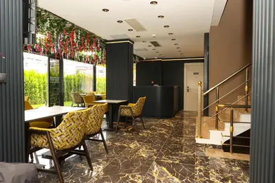 a restaurant with tables and chairs and a staircase at Gardenmode Airport Hotel in Taşoluk