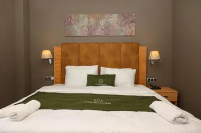 a bedroom with a large bed with a green pillow on it at Gardenmode Airport Hotel in Taşoluk