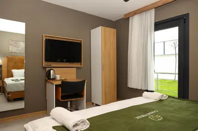 a bedroom with a bed and a desk and a television at Gardenmode Airport Hotel in Taşoluk