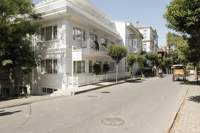 a white building with a horse drawn carriage on a street at Buyukada Cankaya Hotel in Buyukada