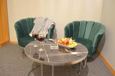 two green chairs and a table with a bowl of fruit and wine glasses at Rosse Hotel in Esenyurt