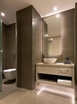 a bathroom with a sink and a toilet and a mirror at AC Hotel Istanbul Macka in Istanbul