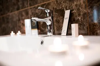 a bathroom sink with a faucet and candles on it at Rox Hotel Istanbul in Istanbul