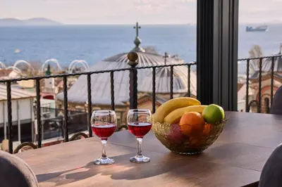 two glasses of wine on a table with a bowl of fruit at Sabina Hotel near Grand Bazaar, city center in Istanbul