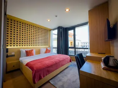 a bedroom with a bed and a desk and a window at Mihman Hotel in Tuzla