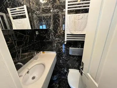 a black tiled bathroom with a sink and a toilet at Gulhane Hotel Old City in Istanbul