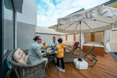 a family sitting at a table on a patio with an umbrella at Luxon Sapanca Family Villas in Sakarya