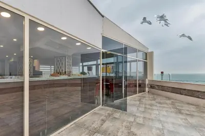 a large glass building with the ocean in the background at Marcello Hotel in Istanbul