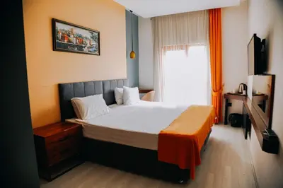 a bedroom with a bed with an orange blanket on it at N&D&D Hotel in Nilüfer