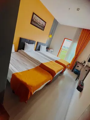 a bedroom with a large bed with an orange blanket at N&D&D Hotel in Nilüfer