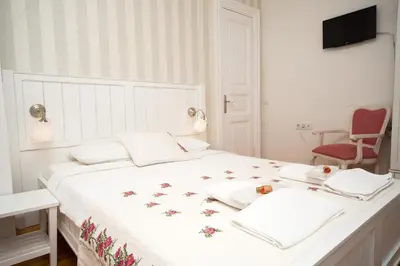 a white bedroom with a large bed with a red chair at Cenar Konak Butik Hotel in Buyukada
