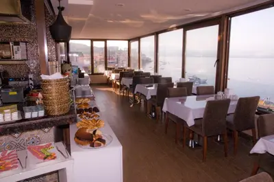 a restaurant with tables and chairs in a room with windows at Kerimbey Hotel in Gemlik
