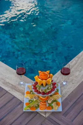 a plate of fruit and wine glasses next to a pool at Sapanca Kokina Suit in Sakarya