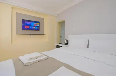 a bedroom with a white bed with a tv on the wall at Lucky Hotel İstanbul in Istanbul
