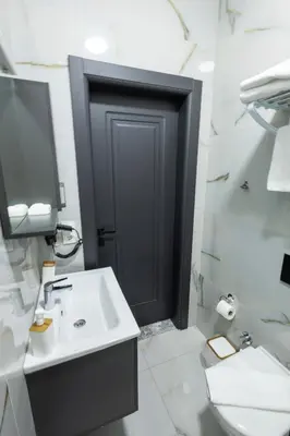 a bathroom with a sink and a black door at Karamürsel Mohti Otel Fitness Organizasyon in Karamusal