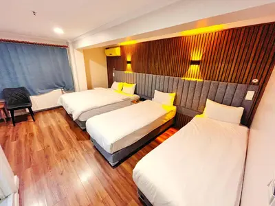 a hotel room with three beds and a chair at Naila Hotel in Istanbul