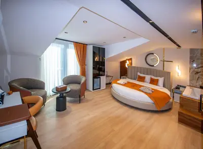 a bedroom with a large bed and two chairs at Elysian Airport Hotel & Restaurant in Arnavutköy