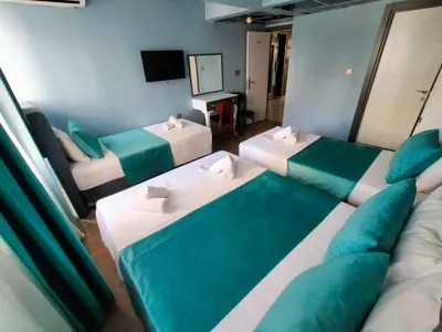 a room with three beds and a couch and a television at Grand Bona Sera Hotel in Istanbul