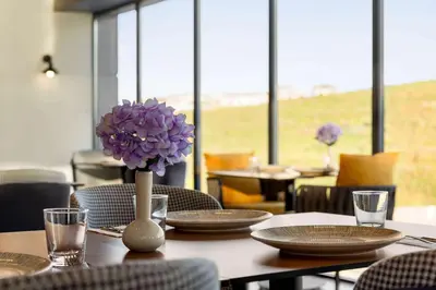a table with plates and a vase with purple flowers at Ramada Encore by Wyndham Istanbul Arnavutkoy in Istanbul