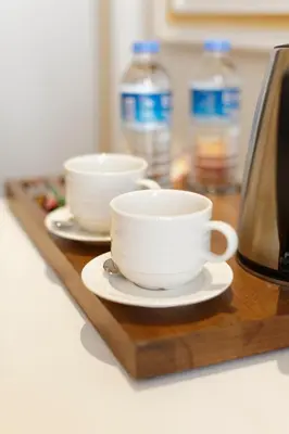 three cups and saucers on a wooden tray with water bottles at Nishant Hotel in Istanbul