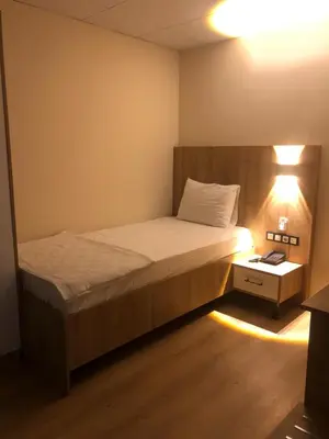 a small bedroom with a bed and a lamp at Vizyon Otel Darıca in Darıca