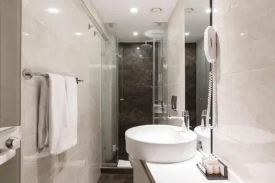 a white bathroom with a sink and a shower at Carina Park Suites Nisantasi in Istanbul