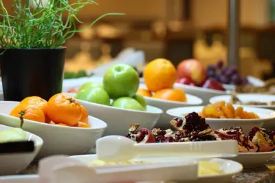 a table topped with bowls of fruit on plates at Luxor Garden Hotel in Kocaeli