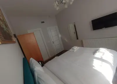 a bedroom with a white bed and a tv at Buyukada Cinar Hotel in Buyukada
