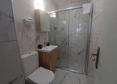 a bathroom with a shower and a toilet and a sink at Buyukada Cinar Hotel in Buyukada