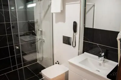 a bathroom with a sink and a shower and a phone at Gorukle Oruc Hotel in Bursa