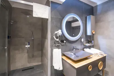 a bathroom with a sink and a shower with a mirror at Shiboo Suite Otel in Gebze