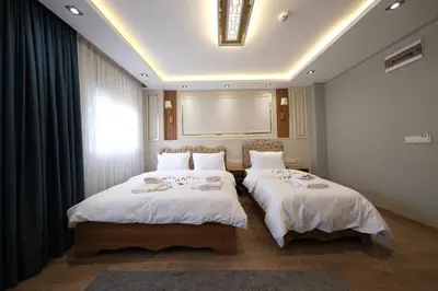 a bedroom with two beds with white sheets and a window at Elita Otel Kumkapı in Istanbul