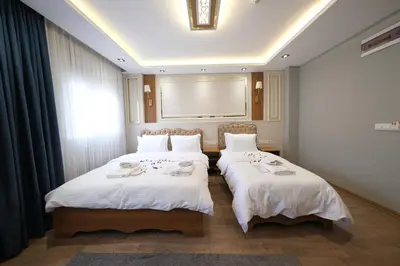 two beds in a hotel room with white sheets at Elita Otel Kumkapı in Istanbul