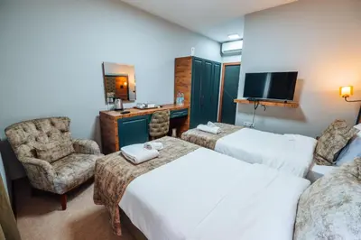 a hotel room with two beds and a chair and a television at Mysia Olympos Hotel in Bursa