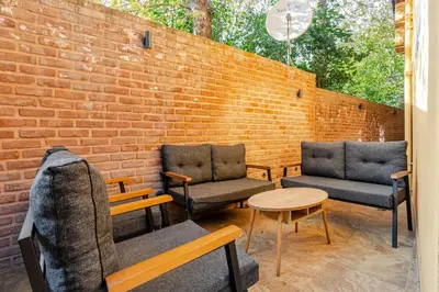 a patio with three chairs and a table and a brick wall at Villa Arancia Istanbul - Garden, BBQ, Sauna & Turkish Bath by the Tram in Fatih in Istanbul