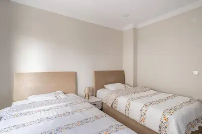 two beds in a bedroom with white walls at Stylish 2BR and 3BR Izmit Apartments- Chic & Cozy in Çavuşçiftliği
