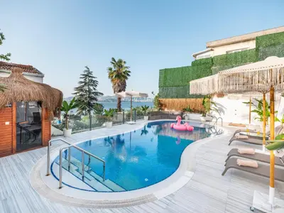 a pool at a resort with chairs and a pink float at Hillora Hotel Buyukada in Adalar