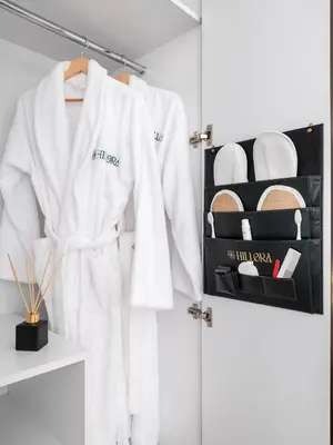 a white robe hanging on a rack in a closet at Hillora Hotel Buyukada in Adalar