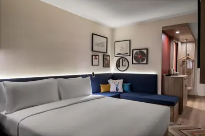 a bedroom with a large bed and a blue bench at Hampton By Hilton Istanbul Merter in Istanbul