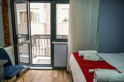 a bedroom with a bed with a red blanket and a balcony at mansion yellow hotel in Istanbul