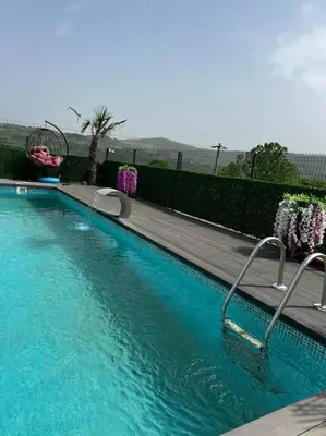 a swimming pool with blue water in front of a fence at MEDASUİTE Stone House With Pool And Jacuzzi in Kandıra