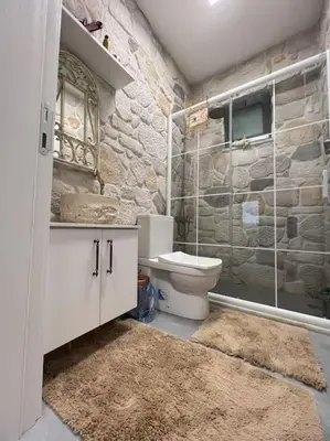 a bathroom with a toilet and a stone wall at MEDASUİTE Stone House With Pool And Jacuzzi in Kandıra