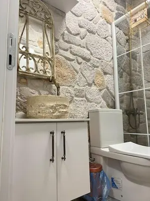 a bathroom with a toilet and a stone wall at MEDASUİTE Stone House With Pool And Jacuzzi in Kandıra
