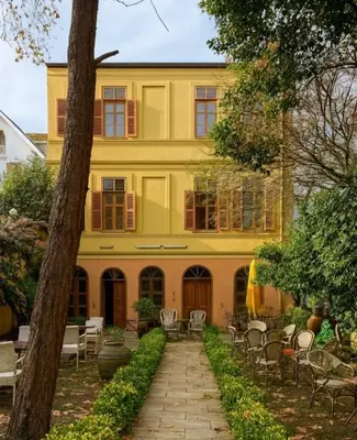 a yellow building with tables and chairs in front of it at Anthea Butik Otel in Adalar