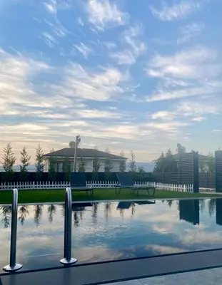 a bench next to a pool of water with a building at High Garden Villas in Sapanca