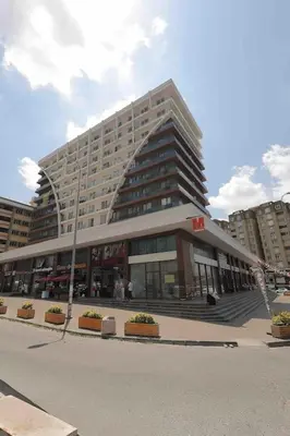 a large building in a city with plants in front of it at Cozy Homes - 2 Rooms & 1 Living room Apartment in Esenyurt