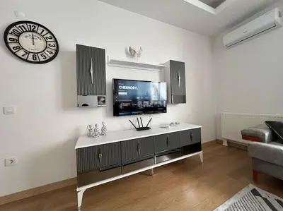 a living room with a tv and a clock on the wall at Cozy Homes 2 Room Apartment Well Designed in Esenyurt