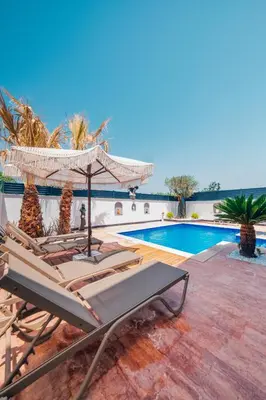 a patio with a pool and chairs and an umbrella at Sapanca Göldibi Suit Bungalov in Sakarya