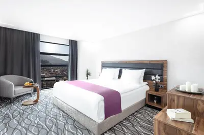 a hotel room with a large bed and a chair at Lilium Hotel & Suites in Bursa