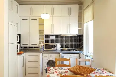 a kitchen with white cabinets and a dishwasher at Super Location Cosy Apartment TaximHome 3 at Taksim Cihangir in Istanbul